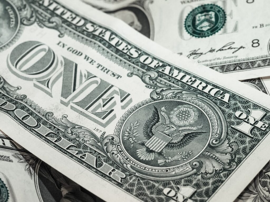 Set of house keys lying next to a single dollar bill on a clean white surface, illustrating the concept of saving money on...