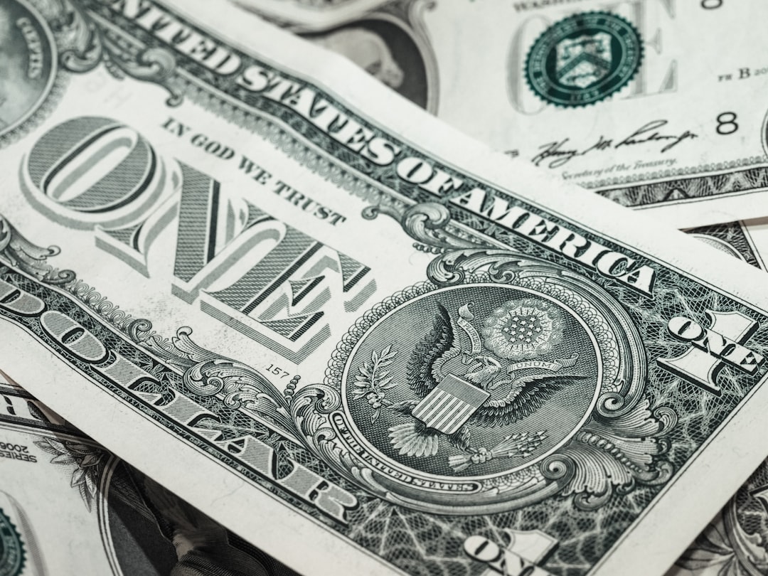 Set of house keys lying next to a single dollar bill on a clean white surface, illustrating the concept of saving money on...