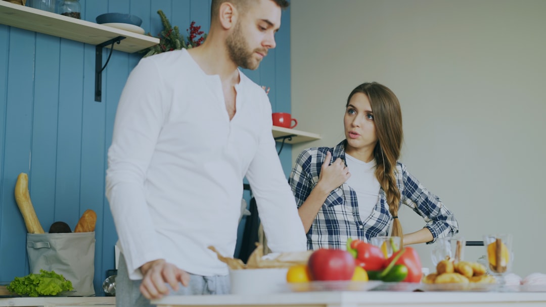 A man and woman sit together at a bright, modern kitchen table with a laptop and coffee, looking happy and relaxed as they review their finances, symbolizing smart investment of their commission savings.