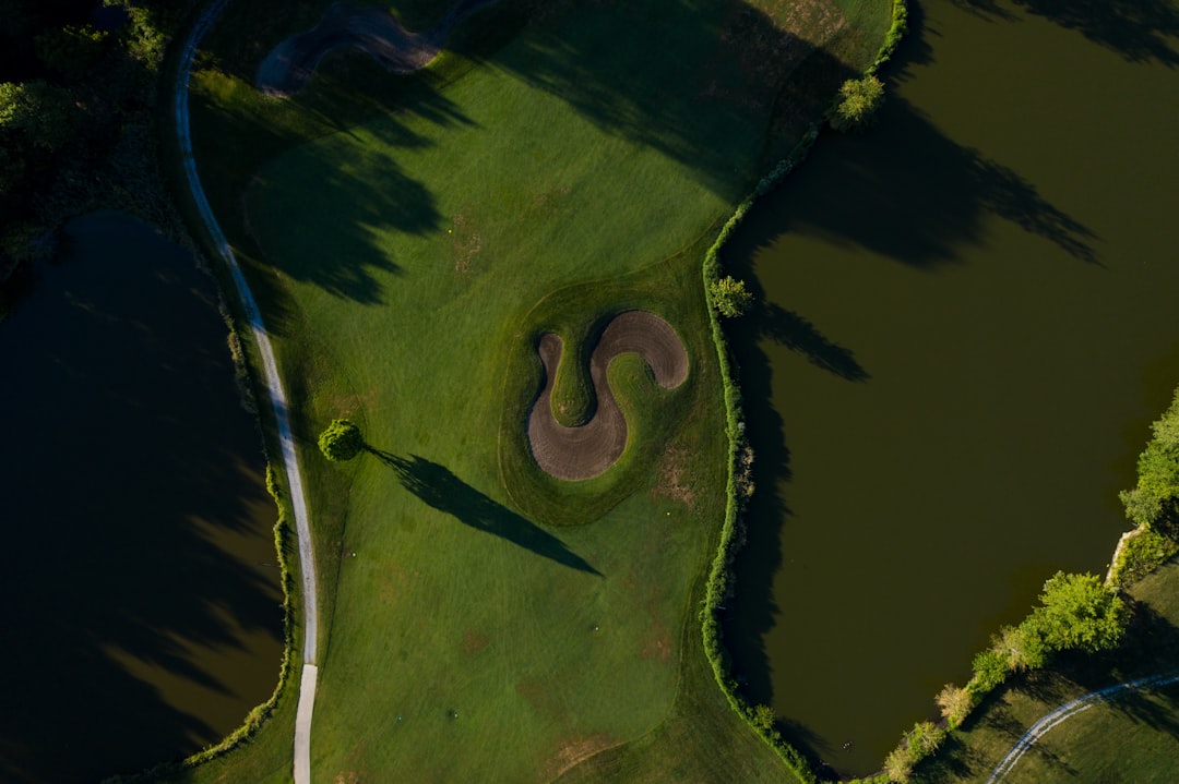 A beautifully manicured, lush green golf course fairway in a luxury residential community under a clear blue sky.
