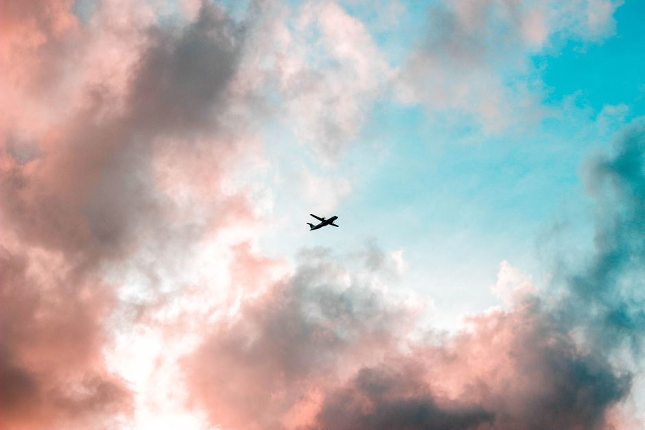 An aerial view of a commercial airplane flying over a clean, modern suburban neighborhood, symbolizing the connection between Louisville's logistics hubs and the housing market.