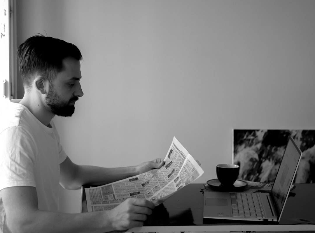 A homeowner sits at a brightly lit desk in their home, carefully reviewing a stack of paperwork, representing the diligence required when selling a property.