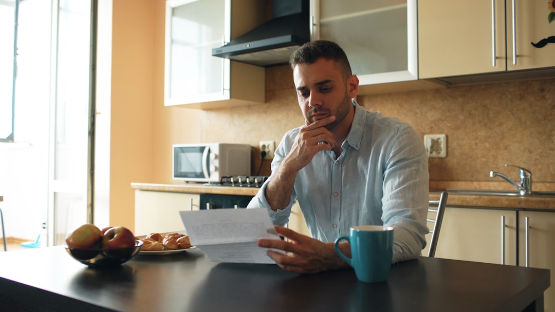 A professional real estate agent sits with a client in a modern setting, pointing to a contract and clearly explaining the details of the home selling paperwork.