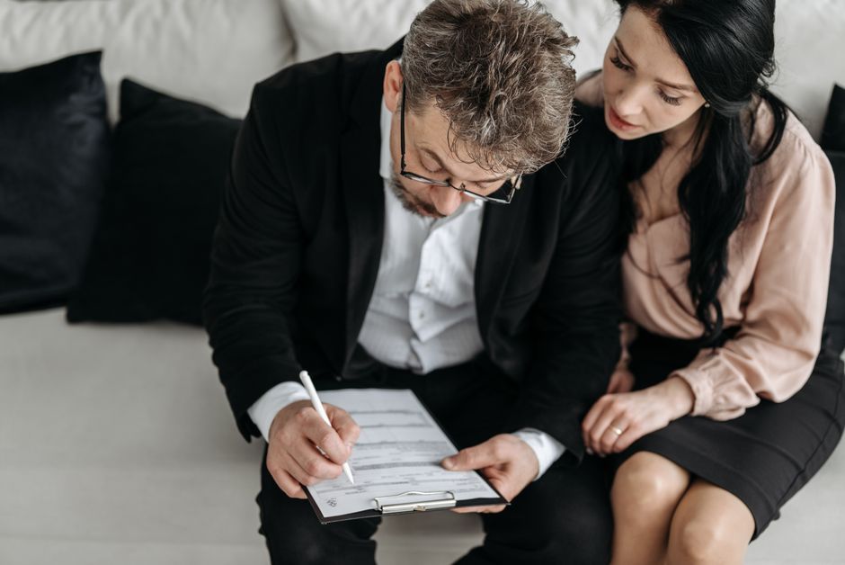 A smiling couple sits at a modern kitchen island reviewing paperwork, feeling confident and happy about their home sale finances.