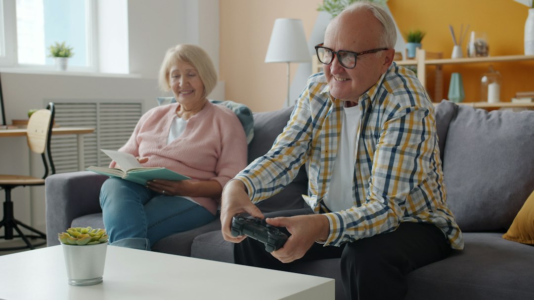 A smiling couple sits together in their bright, modern living room, looking at a tablet as they plan their finances for a future home purchase.
